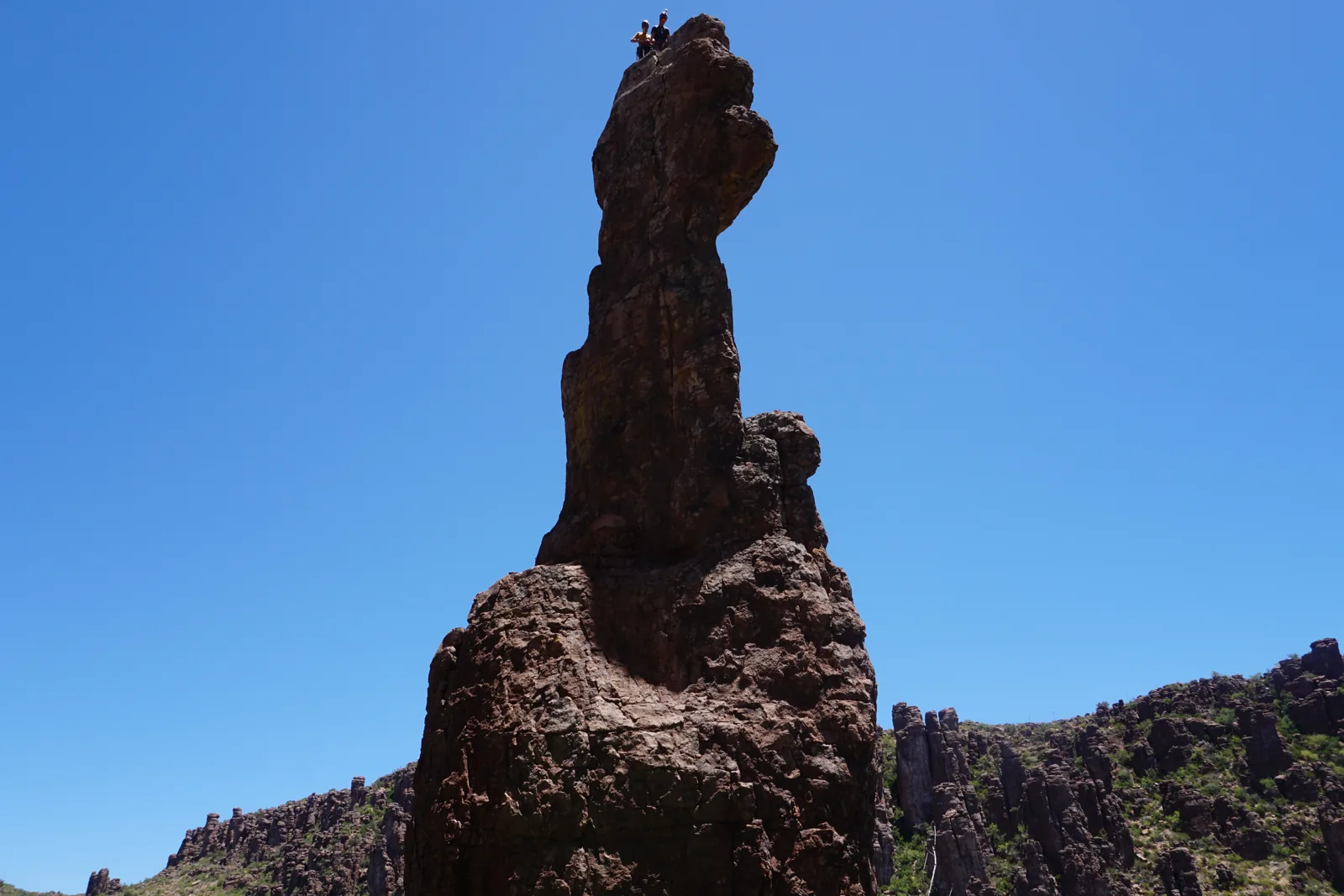 A tall sandstone spire against a clear blue sky